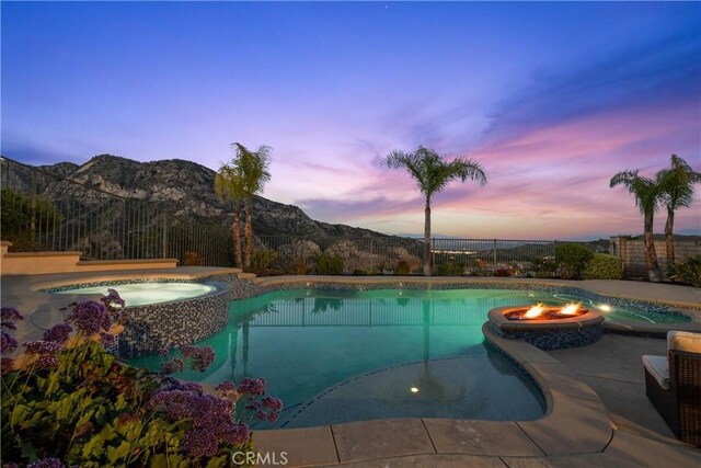25865 Tulip Grove St, Stevenson Ranch, CA 91381 - pool at dusk with a pool with connected hot tub, a mountain view, and a patio area