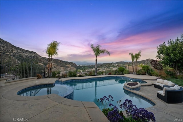 25865 Tulip Grove St, Stevenson Ranch, CA 91381 - pool at dusk with a pool with connected hot tub, a patio, a mountain view, and a fenced backyard