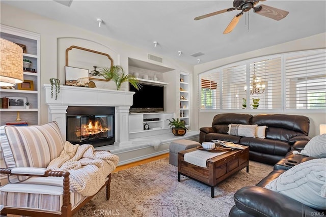 25865 Tulip Grove St, Stevenson Ranch, CA 91381 - living area featuring built in features, ceiling fan, a glass covered fireplace, and wood finished floors