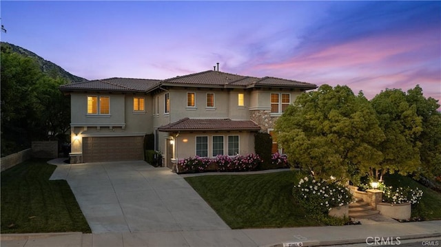 25865 Tulip Grove St, Stevenson Ranch, CA 91381 - mediterranean / spanish house featuring stucco siding, a tiled roof, a garage, driveway, and a yard