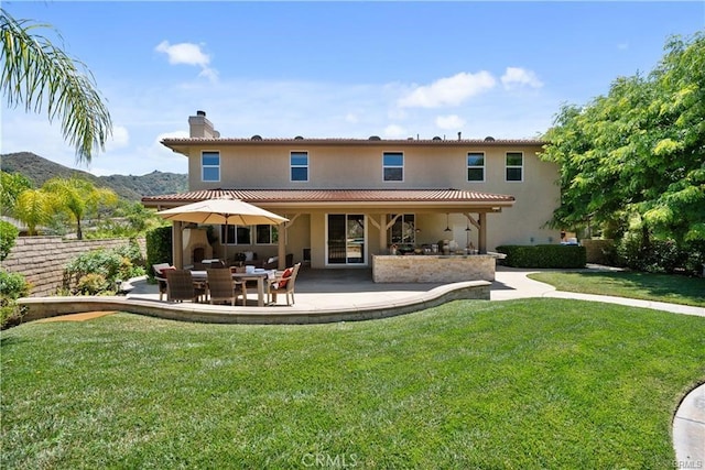25865 Tulip Grove St, Stevenson Ranch, CA 91381 - back of house with a chimney, a patio, a mountain view, a lawn, and stucco siding
