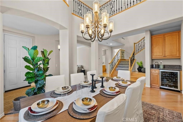 25865 Tulip Grove St, Stevenson Ranch, CA 91381 - dining space featuring wine cooler, arched walkways, stairway, a chandelier, and light wood-style floors