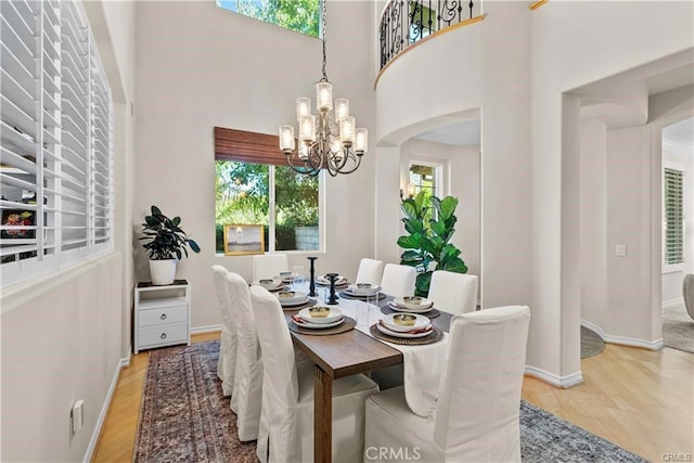 25865 Tulip Grove St, Stevenson Ranch, CA 91381 - dining space with healthy amount of natural light, a chandelier, light wood-style floors, and a towering ceiling