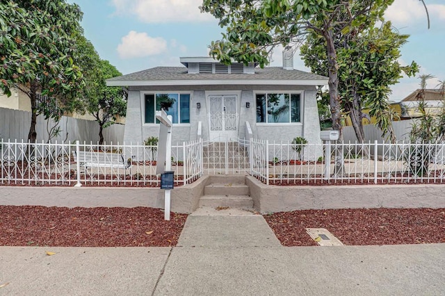 bungalow featuring stucco siding, roof with shingles, a fenced front yard, and a chimney