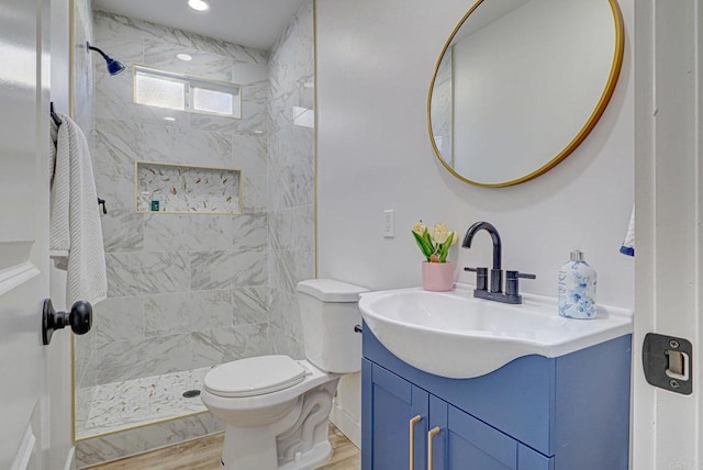 bathroom featuring vanity, toilet, wood finished floors, and a shower stall
