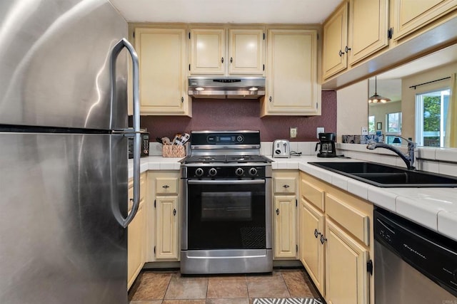 7488 Altiva Pl, Carlsbad, CA 92009 - kitchen featuring appliances with stainless steel finishes, under cabinet range hood, tile countertops, a sink, and cream cabinetry