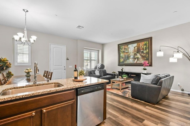 kitchen featuring dishwasher, a sink, a chandelier, open floor plan, and wood finished floors