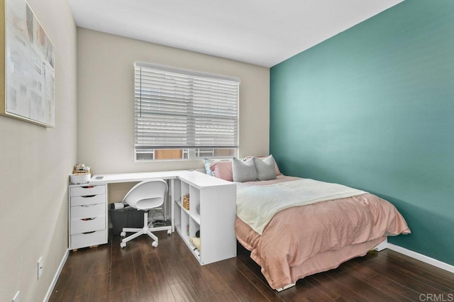 bedroom featuring baseboards, wood finished floors, and an office area