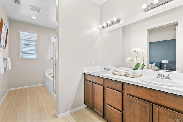 bathroom with double vanity, a tub, ensuite bath, and baseboards