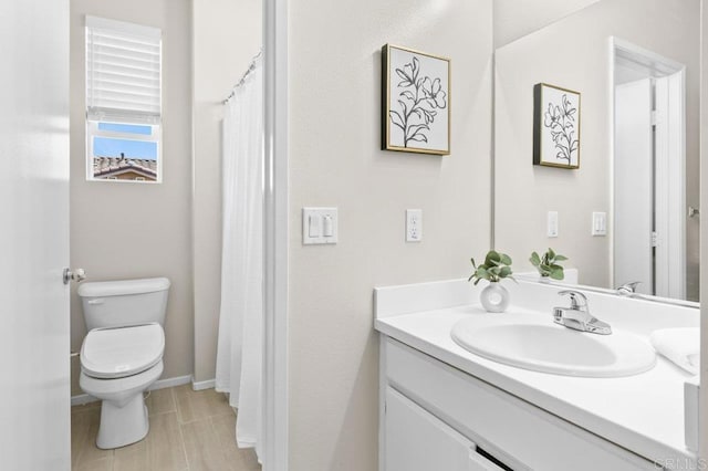 bathroom featuring toilet, vanity, and baseboards