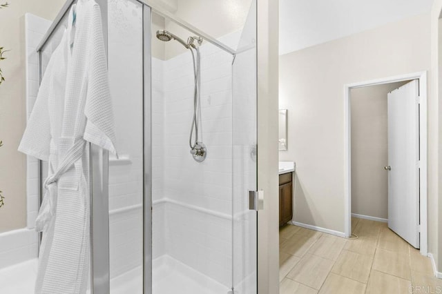 full bath featuring a stall shower, vanity, and baseboards