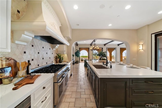 7 Ocean Heights Dr, Newport Coast, CA 92657 - kitchen with arched walkways, range with two ovens, premium range hood, a sink, and tasteful backsplash
