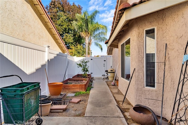 2505 Stuart Ave, Clovis, CA 93611 - view of side of home featuring stucco siding, a garden, a gate, and a fenced backyard