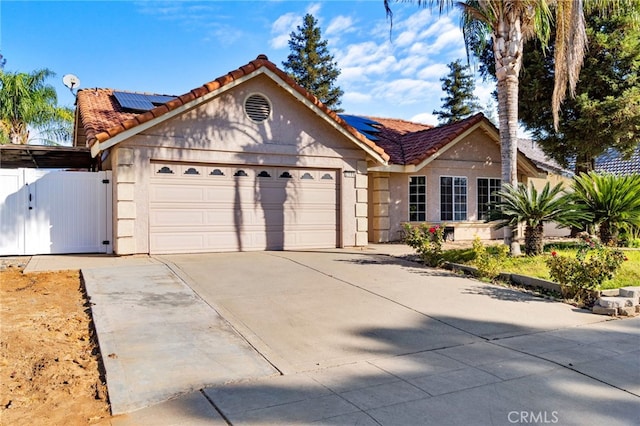 2505 Stuart Ave, Clovis, CA 93611 - ranch-style house featuring a garage, roof mounted solar panels, driveway, and a gate