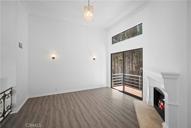 11954 Mayfield Ave Unit 3, Los Angeles, CA 90049 - unfurnished living room with wood finished floors, a lit fireplace, a towering ceiling, crown molding, and baseboards