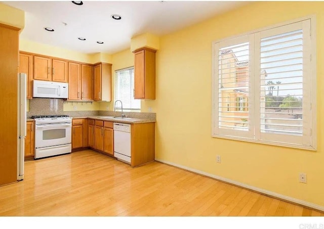 kitchen with white appliances, a sink, light wood-style flooring, tasteful backsplash, and recessed lighting