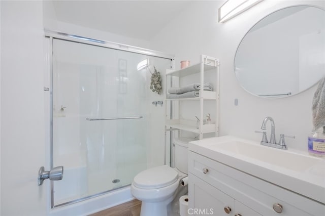 bathroom featuring toilet, a shower stall, vanity, and wood finished floors