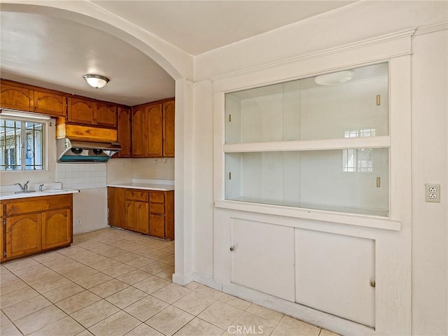 911 N Dos Robles Pl, Alhambra, CA 91801 - kitchen featuring brown cabinetry, a sink, light tile patterned floors, light countertops, and extractor fan