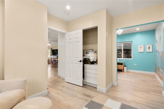hall featuring light wood-style floors, baseboards, and recessed lighting