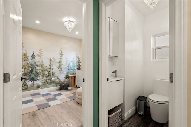 bathroom with a chandelier, wood finished floors, toilet, vanity, and recessed lighting