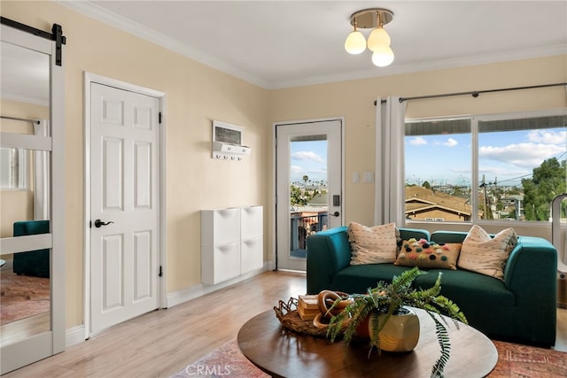 sitting room with light wood-style floors, ornamental molding, a barn door, and baseboards