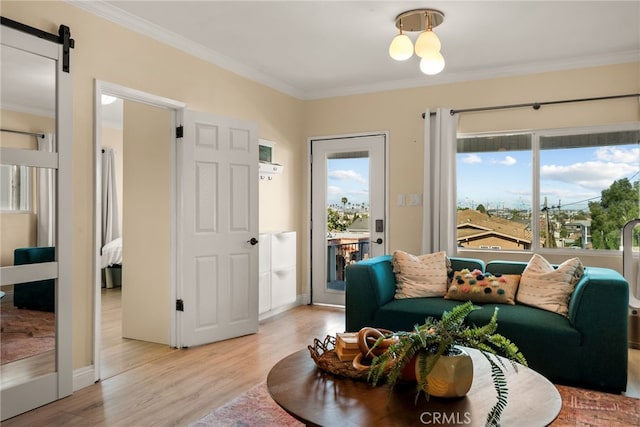 sitting room with light wood-type flooring, ornamental molding, and a barn door