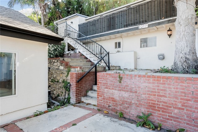 view of side of property featuring stairway and stucco siding