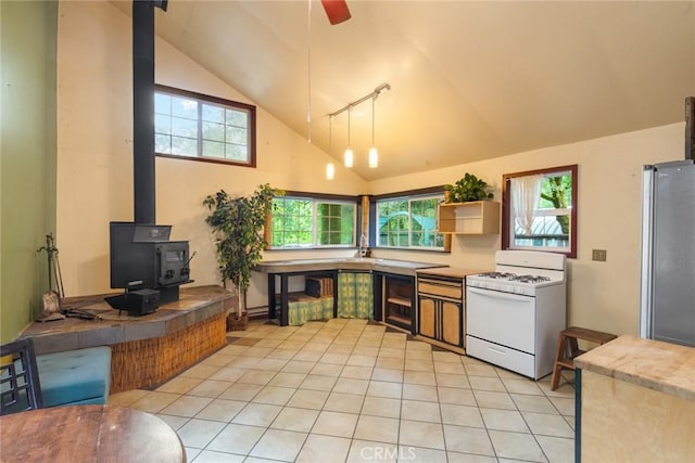 5338 Deception River Rd, Chico, CA 95928 - kitchen with white range with gas stovetop, a wood stove, freestanding refrigerator, light tile patterned flooring, and ceiling fan