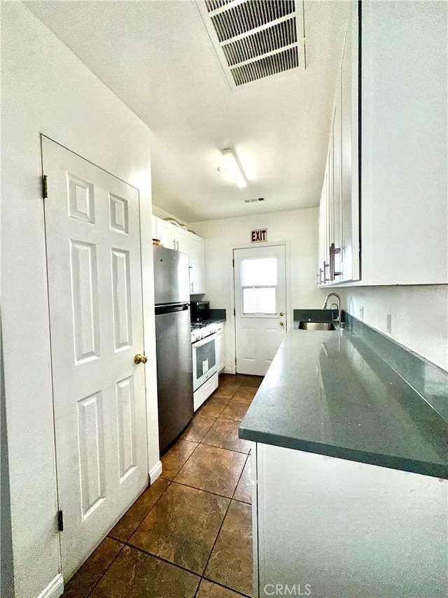 140 S Vendome St, Los Angeles, CA 90057 - kitchen with freestanding refrigerator, white gas range, a sink, white cabinetry, and dark tile patterned floors