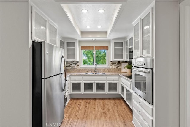 780P Via Los Altos, Laguna Woods, CA 92637 - kitchen featuring stainless steel appliances, a sink, white cabinetry, a tray ceiling, and decorative backsplash