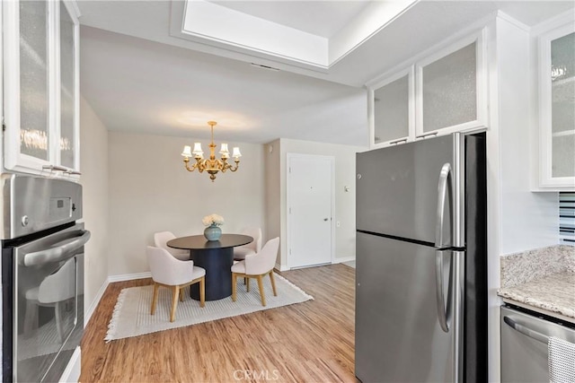 780P Via Los Altos, Laguna Woods, CA 92637 - kitchen featuring stainless steel appliances, a chandelier, light wood finished floors, white cabinetry, and light stone countertops