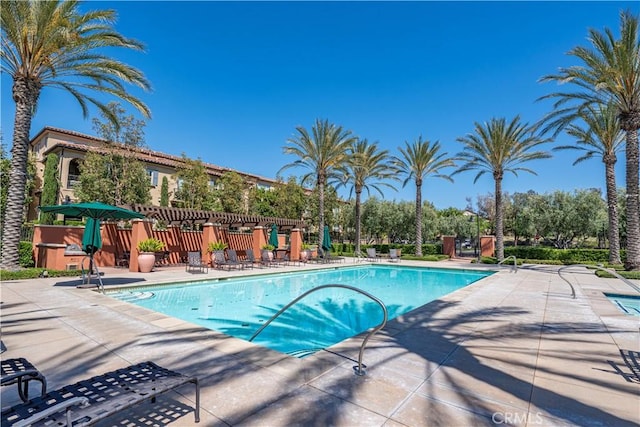 community pool with a patio and fence