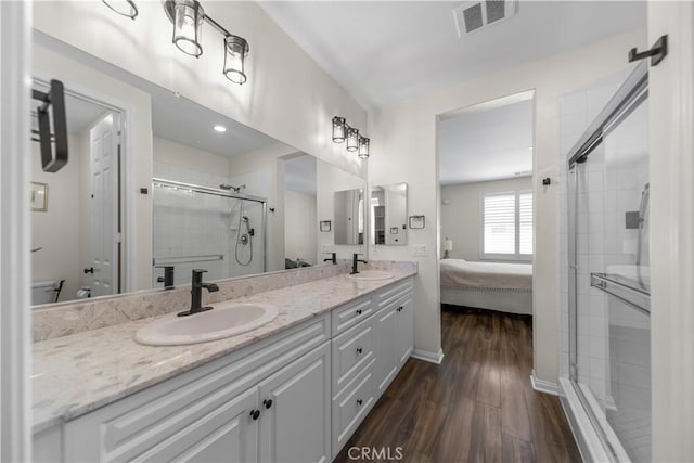 ensuite bathroom with wood finished floors, a stall shower, double vanity, and baseboards