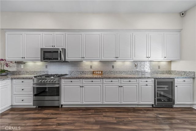 kitchen with stainless steel appliances, beverage cooler, white cabinets, decorative backsplash, and light stone countertops