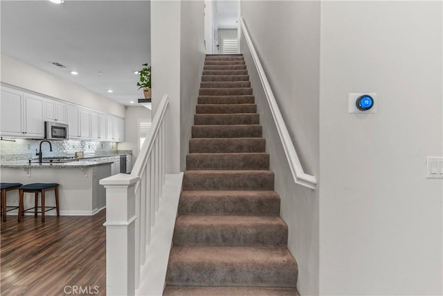 stairway with wood finished floors and recessed lighting