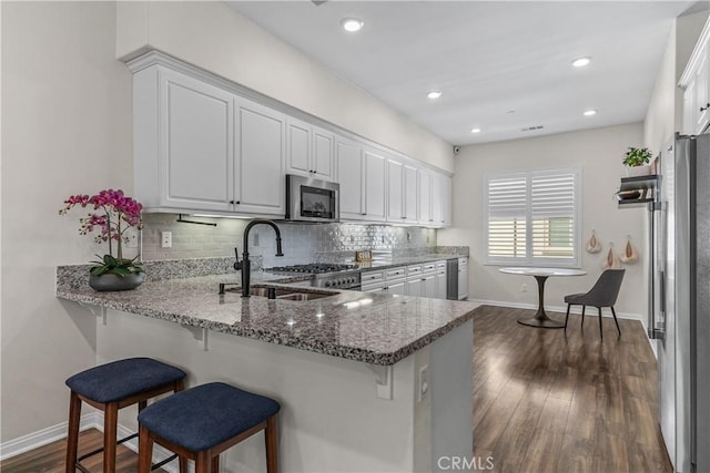 kitchen featuring a sink, stainless steel appliances, white cabinets, tasteful backsplash, and recessed lighting