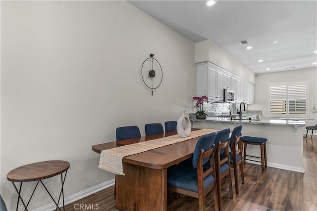 dining area with dark wood-style floors, baseboards, and recessed lighting