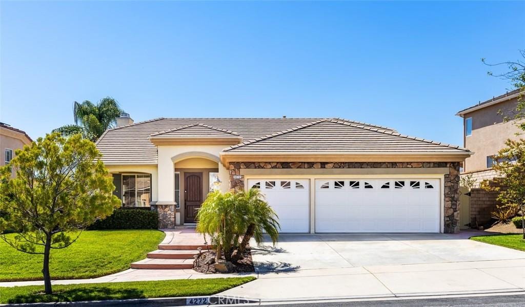 4272 Castlepeak Dr, Corona, CA 92883 - view of front of home featuring concrete driveway, stone siding, an attached garage, a tile roof, and a chimney