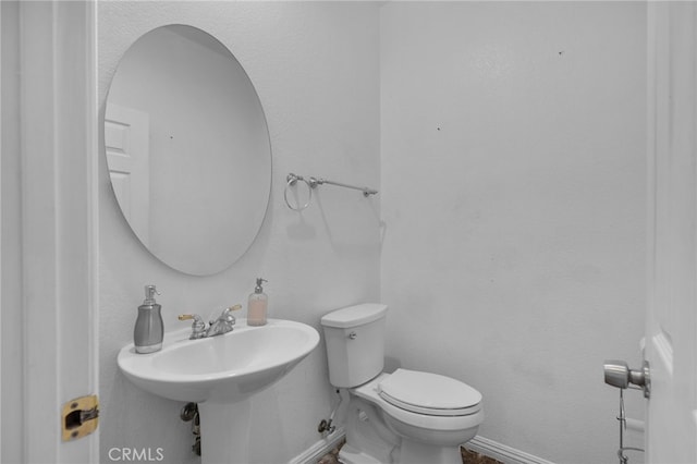 bathroom featuring baseboards and toilet