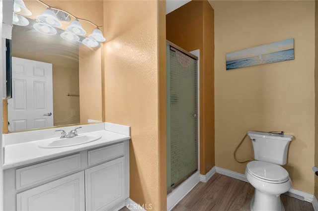 full bath with wood finished floors, a stall shower, toilet, vanity, and baseboards