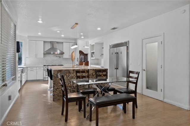 dining area featuring light wood-style flooring, baseboards, and recessed lighting