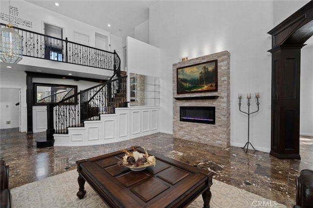 living room with a towering ceiling, marble tiled flooring, stairway, a stone fireplace, and recessed lighting
