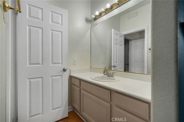 bathroom featuring vanity, a textured wall, and wood finished floors