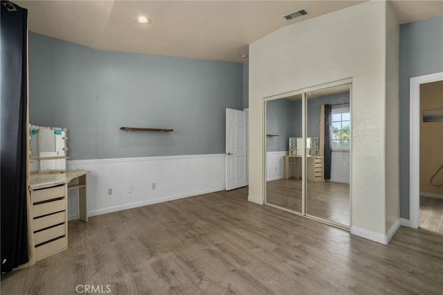 unfurnished bedroom featuring wood finished floors, a wainscoted wall, recessed lighting, a closet, and baseboards