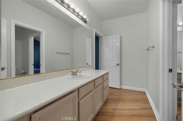 bathroom featuring wood finished floors, baseboards, vanity, and toilet