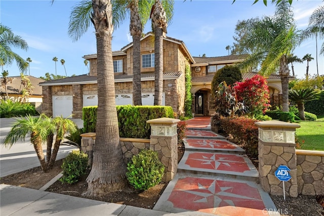 view of front of home with a tile roof, stone siding, a garage, and driveway