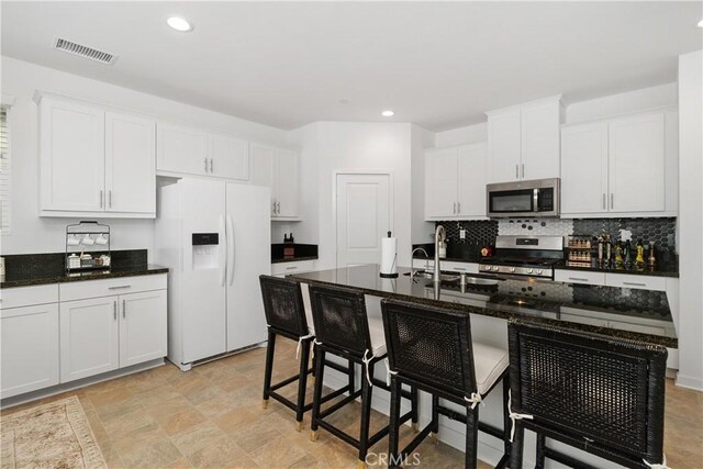 36936 Buccella Ln, Beaumont, CA 92223 - kitchen with appliances with stainless steel finishes, a kitchen breakfast bar, tasteful backsplash, white cabinets, and recessed lighting