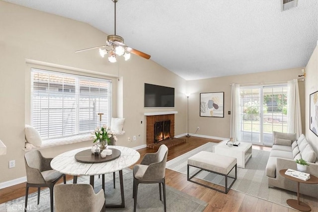 1866 Overland St, Colton, CA 92324 - living room with lofted ceiling, a ceiling fan, wood finished floors, a brick fireplace, and a textured ceiling