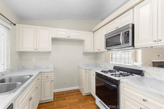 1866 Overland St, Colton, CA 92324 - kitchen with stainless steel microwave, white gas range, light wood-style floors, vaulted ceiling, and white cabinets