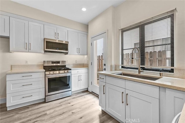 547 N Wilson Ave Unit 2, Pasadena, CA 91106 - kitchen with appliances with stainless steel finishes, a sink, white cabinets, light wood finished floors, and recessed lighting